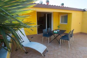 a patio with a table and chairs and a yellow house at Le Palme Sona in Sona