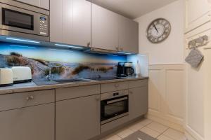 a kitchen with a sink and a clock on the wall at Hus op de Dün Eiderente in Sankt Peter-Ording