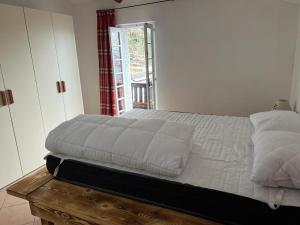 Schlafzimmer mit einem Bett mit weißer Bettwäsche und einem Fenster in der Unterkunft Camera matrimoniale con terrazza panoramica in Serina
