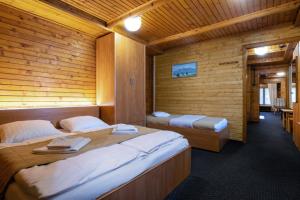 een slaapkamer met 2 bedden in een houten kamer bij Chata Pri potoku in Stará Lesná