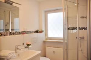 a white bathroom with a shower and a sink at Haus am Wiesengrund in Reit im Winkl