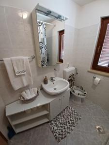 een badkamer met een wastafel, een toilet en een spiegel bij Lovely Apartment Piantade in Poreč