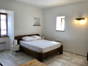 Schlafzimmer mit einem Bett mit weißer Bettwäsche und einem Fenster in der Unterkunft Auberge Les Grillons in Meyras