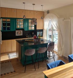 a kitchen with a green island with bar stools at Laimas in Jūrmala