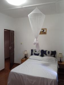 Un dormitorio con una cama blanca con una red blanca en Landa's Guest House, en Praia do Tofo