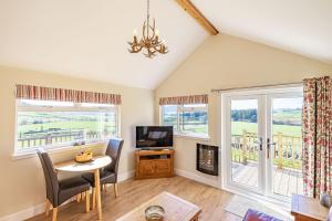 a living room with a table and a tv and windows at Pine Marten Lodge with Hot Tub in Cray