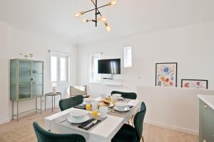 une salle à manger avec une table blanche et des chaises vertes dans l'établissement BmyGuest - Alfama 2 Apartment, à Lisbonne