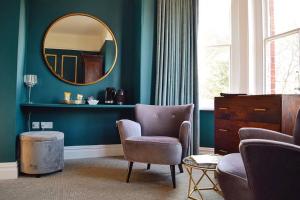 a living room with a mirror and chairs and a dresser at Blakeney House in Blakeney