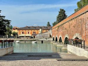 een brug over een rivier naast een stenen muur bij Casa Olympia in Peschiera del Garda