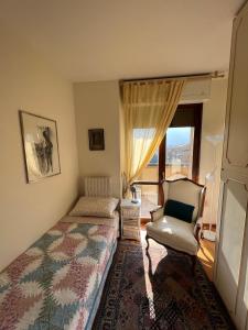a bedroom with a bed and a chair and a window at CLASSY Penthouse B&B in Imola