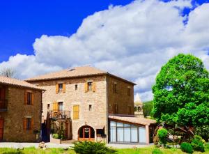 a large brick building with a tree in the background at Auberge Les Grillons in Meyras