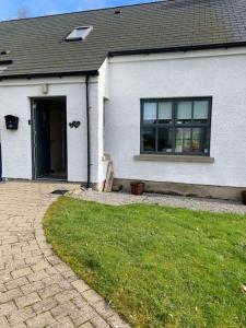 a white house with a door and a grass yard at Serenity Cottage in Lisnaskea