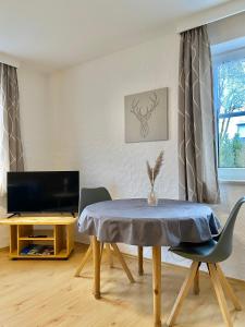 een woonkamer met een tafel en een televisie bij Gästehaus Frankenwaldhof in Bad Steben