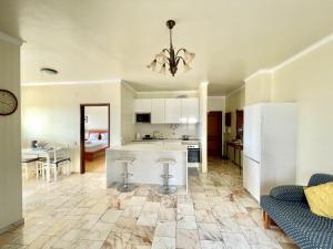 een keuken en een woonkamer met een bank en een kroonluchter bij Cosy Sea View Apartment in Costa da Caparica