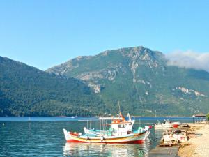 a group of boats sitting on the water with a mountain at Asteri Apartments Mytikas 2-Bedroom Seaview Courtyard in Mitika