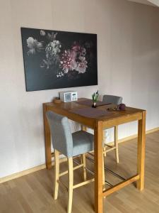 uma mesa de madeira com duas cadeiras e uma pintura na parede em Ferienwohnung Seeblick em Northeim