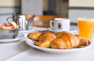 ein Teller Croissants und eine Schüssel mit Obst und Orangensaft in der Unterkunft Hotel La Perla in Buenos Aires