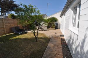 a backyard with a wooden walkway next to a house at Petite maison cosy-9mn à pied gare, 5 mn plage ! in Pornichet