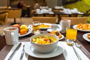 a table with a bowl of fruit and plates of food at Empire Marquês Hotel in Lisbon