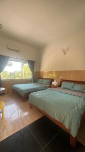 a bedroom with two beds and a window at Bao Dien Guesthouse in Bao Loc +5 photos