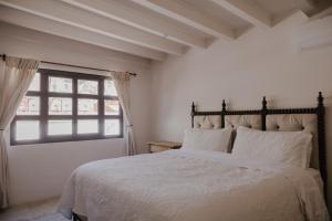 a bedroom with a bed with white sheets and a window at Casa Chiquitos in San Miguel de Allende