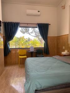 a bedroom with a bed and a window with two chairs at Bao Dien Guesthouse in Bao Loc