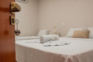 2 camas con sábanas blancas y toallas. en Pousada Chayenne, en Piranhas