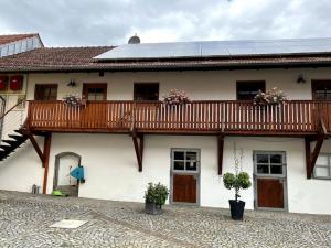 a white house with a wooden balcony on it at Ferienwohnung Vierseithof in Eging am See