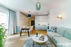 ein Wohnzimmer mit einem Sofa und einem Tisch in der Unterkunft Apartamenty BalticON Polanki Aqua in Kołobrzeg