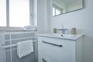 ein weißes Badezimmer mit einem Waschbecken und einem Spiegel in der Unterkunft Rantum Raanwai 21 in Rantum