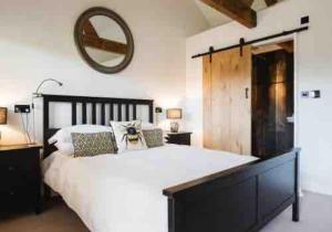 a bedroom with a large white bed and a mirror at Dovecote in Chipping Campden