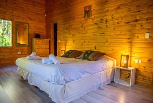 1 dormitorio con 1 cama grande en una pared de madera en BOG Budas del Bosque en Villa La Angostura