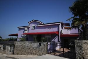 a white house with a fence and a palm tree at ApartHotel Viola in Pula