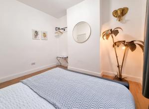 a bedroom with a bed and a mirror and a plant at Designer Flat with Parking near Peckham & Brixton in London