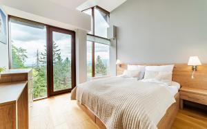 a bedroom with a large bed and large windows at Apartamenty Sun & Snow Resorts in Szklarska Poręba