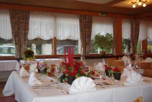 un comedor con mesas blancas con flores. en Hotel Adler, en Sigriswil