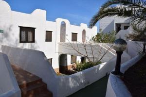 un edificio blanco con una palmera delante en Appartement in Betancuria mit Garten und gemeinsamem Pool, en Valle de Santa Inés