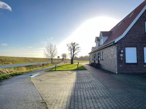 ein Backsteingebäude auf einer Straße neben einem Feld in der Unterkunft Ferienwohnung Sonne&Meer in Dornum