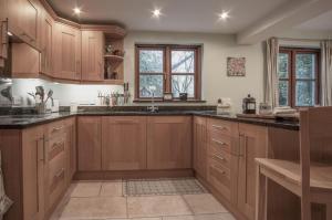 a kitchen with wooden cabinets and a sink at Llais Afon - 3 Bedroom Holiday Home - Fishguard in Fishguard