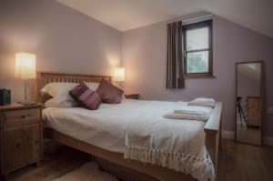 Schlafzimmer mit einem Bett mit einem Spiegel und einem Fenster in der Unterkunft Llais Afon - 3 Bedroom Holiday Home - Fishguard in Fishguard
