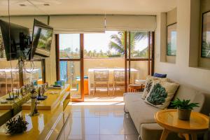 ein Wohnzimmer mit Sofa und Tisch in der Unterkunft Cobertura com Piscina Privativa em Barra Bali, Pé na Areia, à Beira-Mar - Destino BSM 417 in Barra de São Miguel
