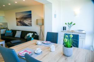 uma sala de estar com uma mesa de madeira e cadeiras azuis em Am Sahlenburger Strand AS01 em Cuxhaven