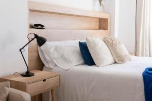 a bed with white pillows and a lamp on a table at La Sort Boutique Hotel in Moraira