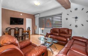 a living room with leather furniture and a clock on the wall at Apartments Sweet Home in Otočac