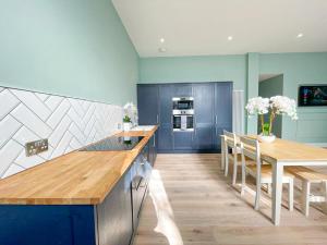 a kitchen with blue cabinets and a table and chairs at Beautiful 2BR, Private Entry in Vibrant Leith in Edinburgh