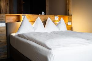 a large white bed with white pillows on it at Alpenblick Weggis - Panorama & Alpen Chic Hotel in Weggis