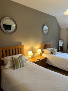 a hotel room with two beds and two mirrors at Groves Barn at Norton Grounds in Chipping Campden