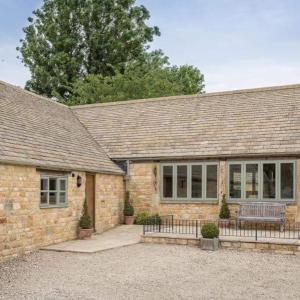 ein Backsteinhaus mit einer Bank davor in der Unterkunft Groves Barn at Norton Grounds in Chipping Campden