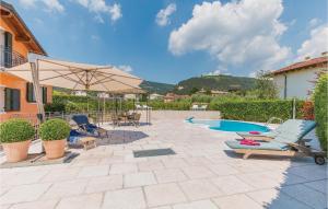 Un patio con sillas y sombrilla y una piscina. en Nice Home In Fumane -Vr-, en Fumane