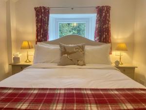 sypialnia z dużym łóżkiem z poduszkami i oknem w obiekcie Edgcott House w mieście Exford